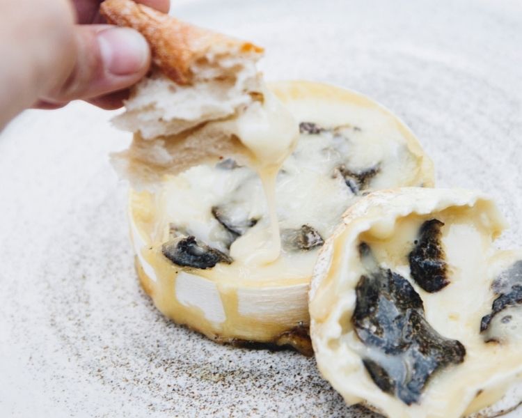 bread being dipped into melted truffle cheese