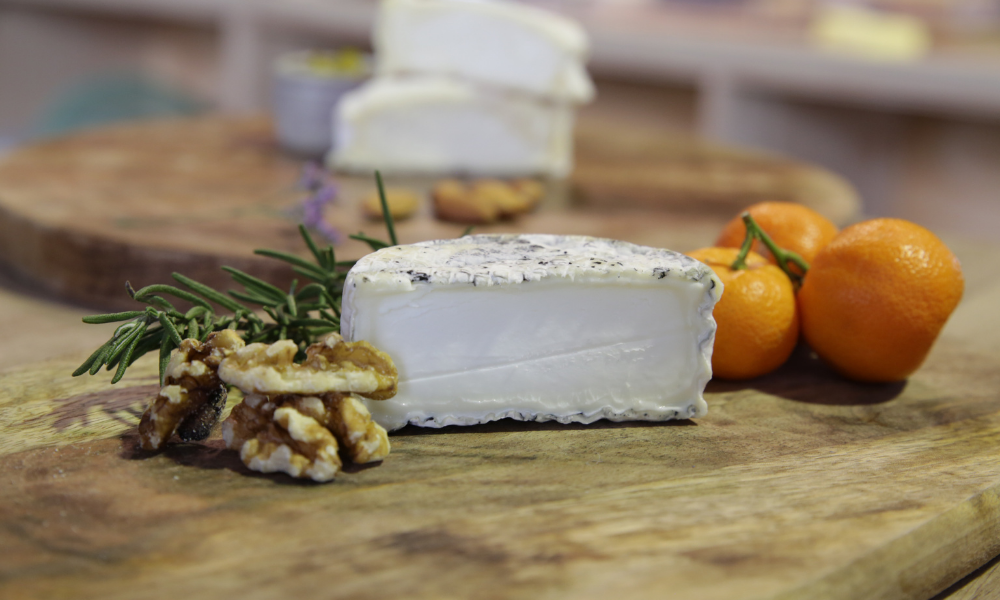 soft cheese on a board with tomatos and walnuts on the side